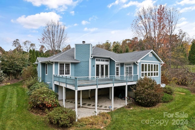 back of property with a deck and a lawn