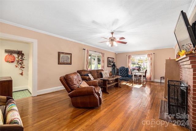 living room featuring hardwood / wood-style floors, a fireplace, ceiling fan, and crown molding