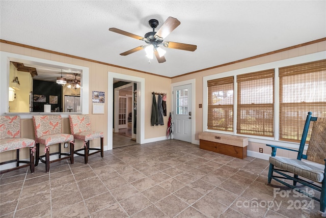 living area with a textured ceiling, ceiling fan, and ornamental molding