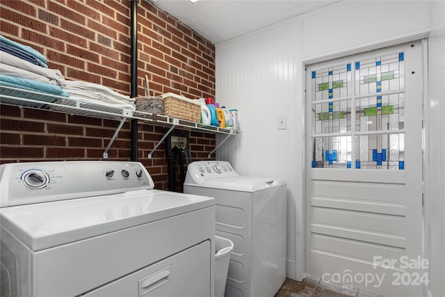 washroom featuring washer and dryer and brick wall