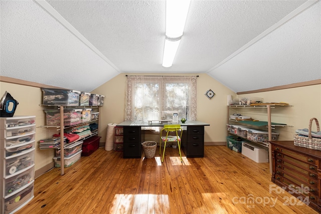 office area featuring light hardwood / wood-style floors, a textured ceiling, and vaulted ceiling