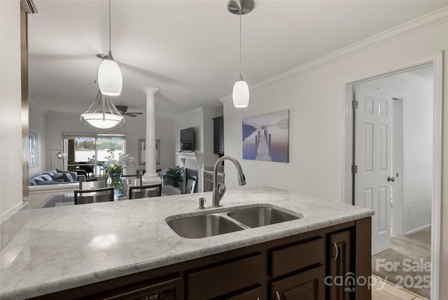 kitchen with light carpet, dark brown cabinets, sink, decorative light fixtures, and light stone counters