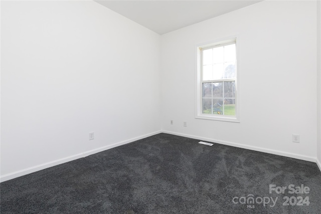 unfurnished room with dark carpet