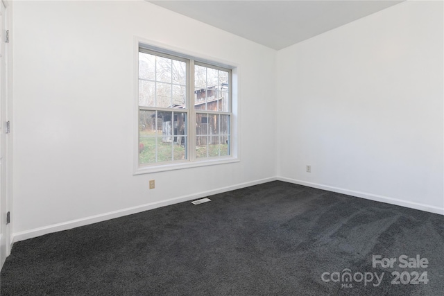 spare room featuring dark colored carpet