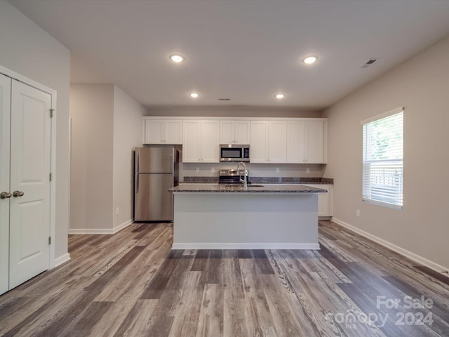 kitchen with white cabinets, dark hardwood / wood-style flooring, stainless steel appliances, and dark stone counters