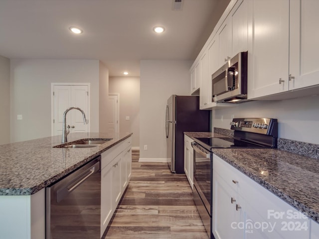 kitchen featuring dark stone counters, sink, white cabinetry, wood-type flooring, and stainless steel appliances