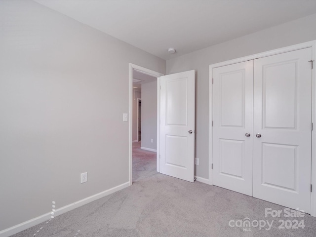 unfurnished bedroom with light carpet and a closet