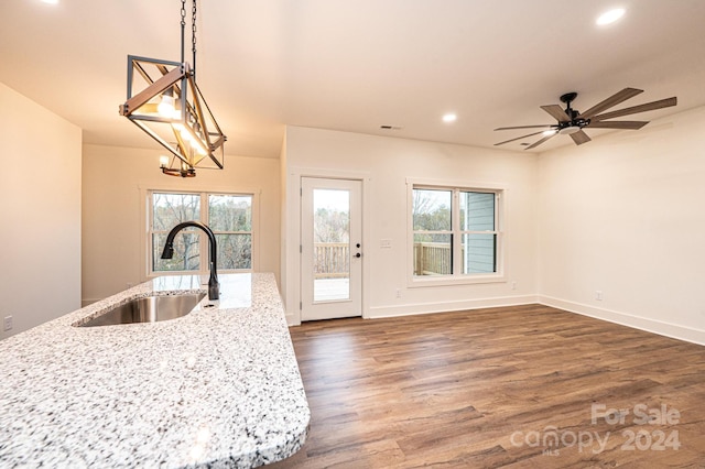 kitchen featuring light stone countertops, sink, hanging light fixtures, and dark hardwood / wood-style floors