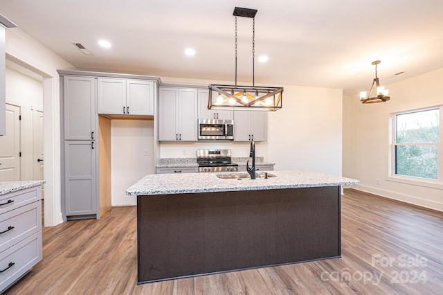 kitchen featuring hardwood / wood-style flooring, a kitchen island with sink, sink, and appliances with stainless steel finishes