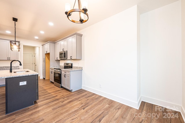 kitchen featuring appliances with stainless steel finishes, light hardwood / wood-style flooring, pendant lighting, and gray cabinetry