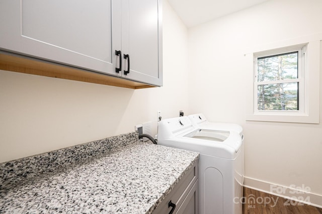 washroom featuring washing machine and clothes dryer, dark wood-type flooring, and cabinets