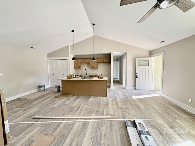 kitchen with a kitchen island with sink, sink, hanging light fixtures, ceiling fan, and light hardwood / wood-style floors