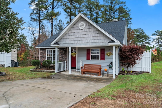 view of front of property with a front yard, a porch, and cooling unit