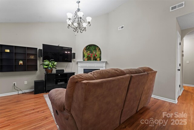 living room with a fireplace, wood finished floors, visible vents, and baseboards