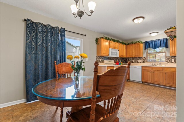 dining area featuring baseboards, light tile patterned floors, and an inviting chandelier