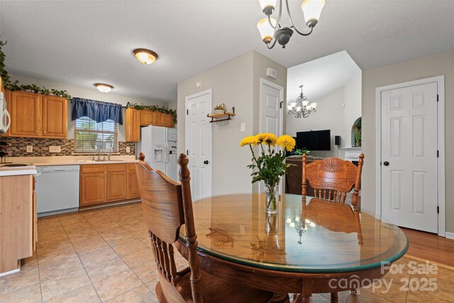 dining space featuring a chandelier, a textured ceiling, and light tile patterned floors