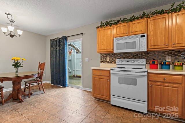 kitchen featuring light countertops, white appliances, brown cabinetry, and a notable chandelier