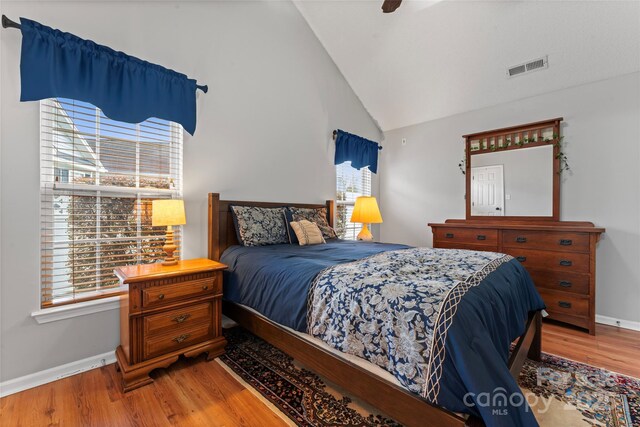 bedroom with a ceiling fan, visible vents, baseboards, and wood finished floors