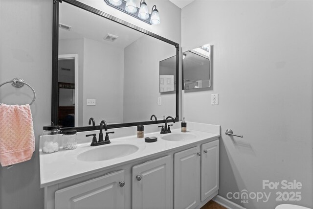 bathroom featuring visible vents, a sink, and double vanity