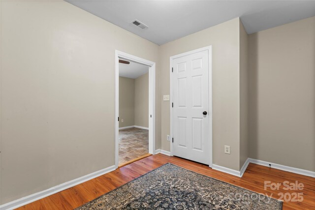 spare room with wood finished floors, visible vents, and baseboards