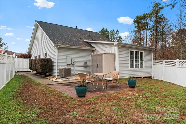 rear view of property with an outbuilding, a patio area, a fenced backyard, and cooling unit