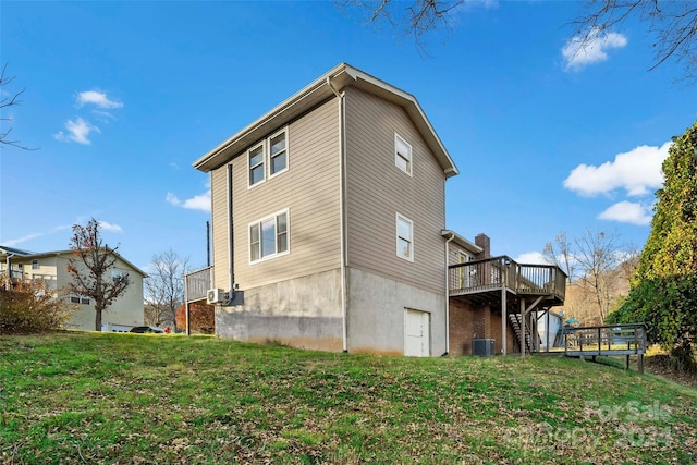 rear view of property with a lawn, central AC unit, and a wooden deck