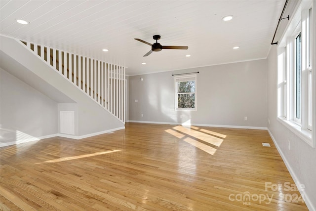 unfurnished living room featuring ceiling fan, ornamental molding, and light wood-type flooring