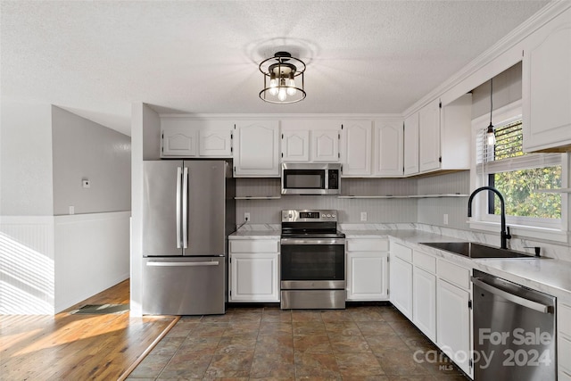 kitchen featuring decorative light fixtures, white cabinetry, sink, and appliances with stainless steel finishes