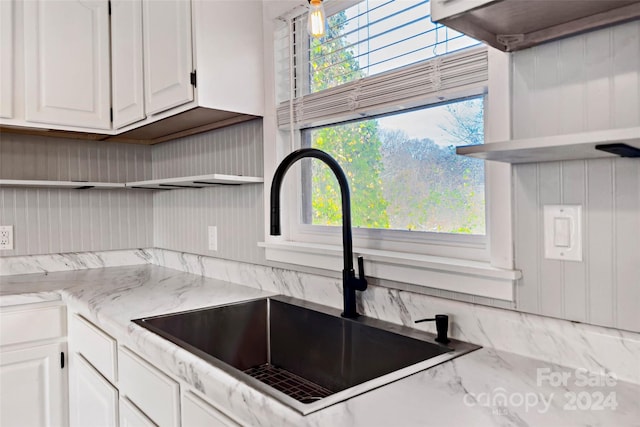 kitchen with light stone countertops, sink, and white cabinets