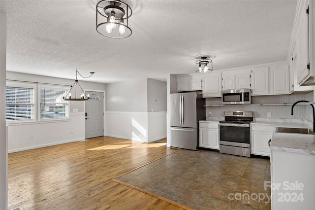 kitchen with pendant lighting, sink, dark hardwood / wood-style floors, appliances with stainless steel finishes, and white cabinetry