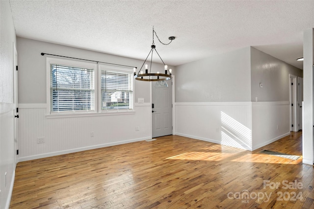 interior space with a chandelier, a textured ceiling, and light hardwood / wood-style flooring