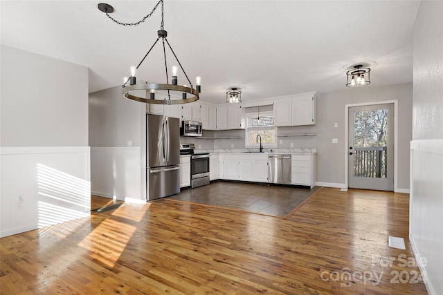 kitchen featuring hanging light fixtures, stainless steel appliances, white cabinetry, and dark hardwood / wood-style floors