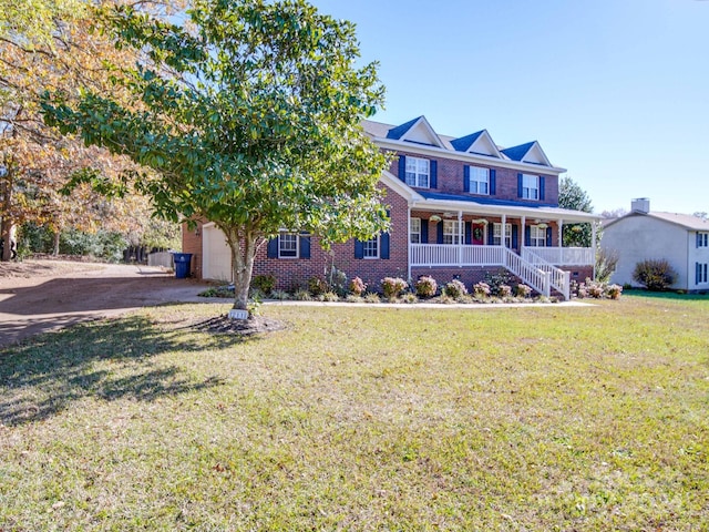 view of front of home featuring a garage, covered porch, and a front yard