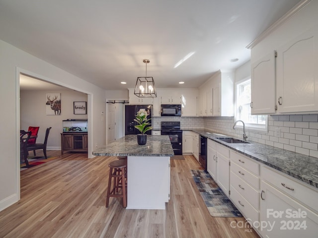 kitchen featuring black appliances, a center island, white cabinetry, and sink