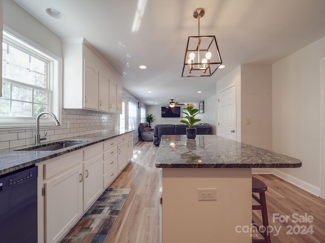 kitchen featuring sink, decorative light fixtures, black dishwasher, light hardwood / wood-style floors, and white cabinetry