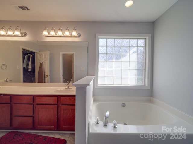 bathroom featuring tile patterned floors, vanity, and a tub to relax in