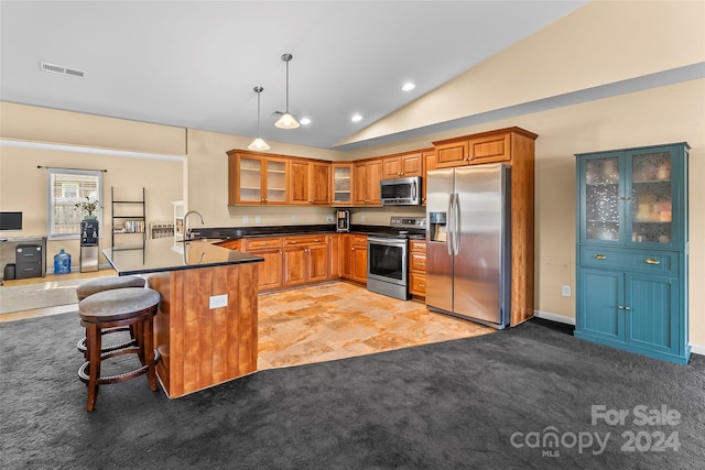 kitchen featuring kitchen peninsula, appliances with stainless steel finishes, a breakfast bar, vaulted ceiling, and decorative light fixtures