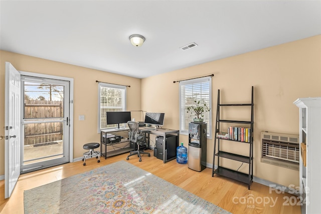 office featuring light hardwood / wood-style floors, a wealth of natural light, and heating unit