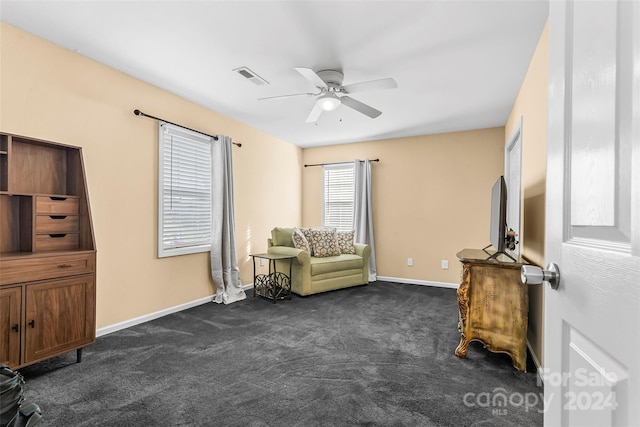 living area with ceiling fan and dark carpet