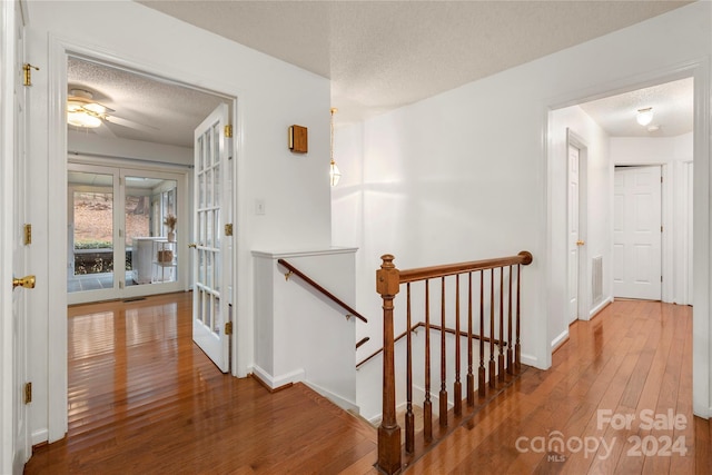 hall featuring hardwood / wood-style flooring, a textured ceiling, and french doors