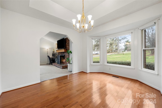 unfurnished dining area featuring hardwood / wood-style floors, a notable chandelier, and a fireplace