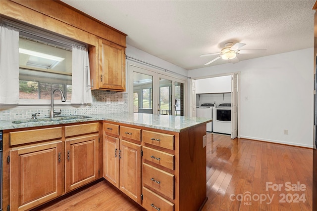 kitchen with kitchen peninsula, washing machine and dryer, plenty of natural light, and sink