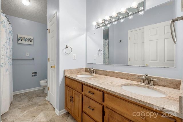 bathroom with vanity, toilet, and a textured ceiling