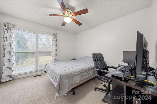 carpeted bedroom featuring multiple windows, ceiling fan, and a textured ceiling