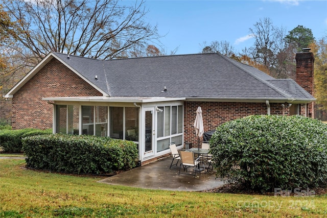 rear view of house with a sunroom, a patio area, and a lawn