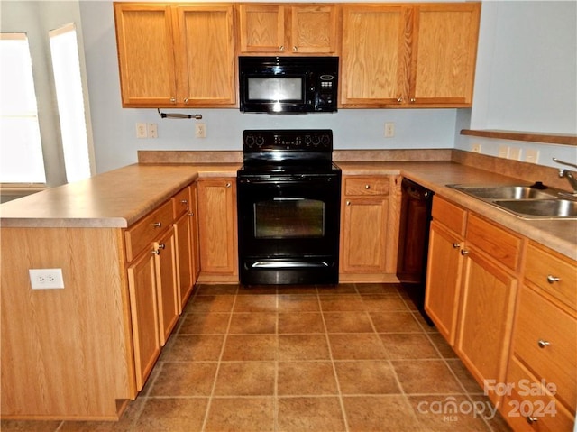 kitchen with kitchen peninsula, sink, dark tile patterned floors, and black appliances