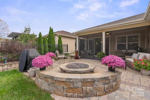 view of patio featuring grilling area, a sunroom, ceiling fan, and a fire pit