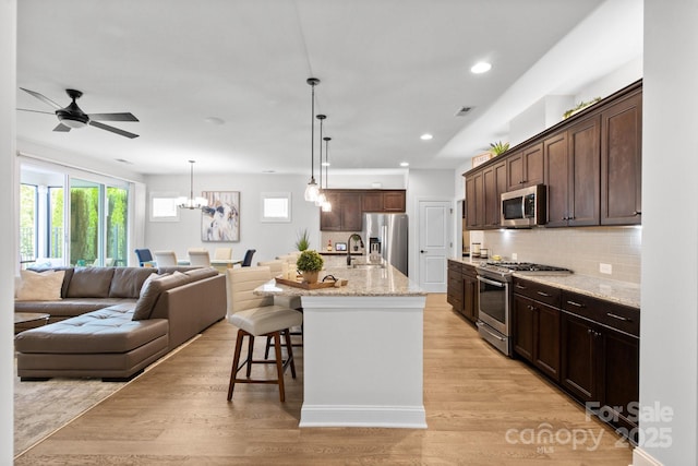 kitchen with a kitchen breakfast bar, tasteful backsplash, stainless steel appliances, a kitchen island with sink, and sink