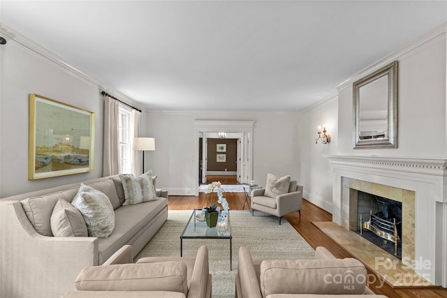 living room featuring a premium fireplace, wood finished floors, crown molding, and baseboards