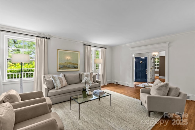 living room featuring crown molding, wood finished floors, baseboards, and a chandelier